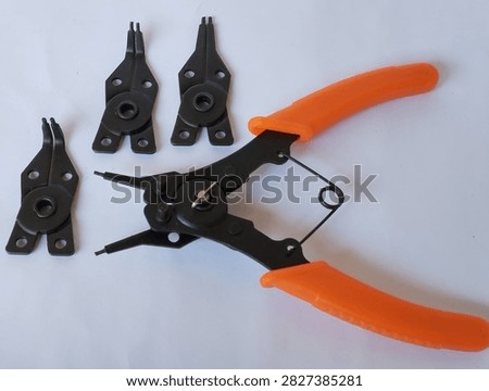 Four in one snap ring pliers with interchangeable tips and orange handles isolated on a white background