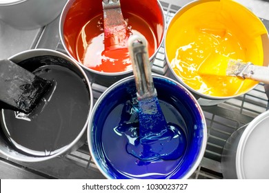 Four open buckets with CMYK paints at the printing manufacturing