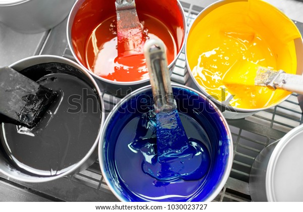 Four open buckets with CMYK paints at the printing manufacturing