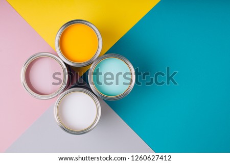 Four open cans of paint on bright symmetry background. Yellow, white, pink, turquoise colors of paint. Place for text. Renovation concept.