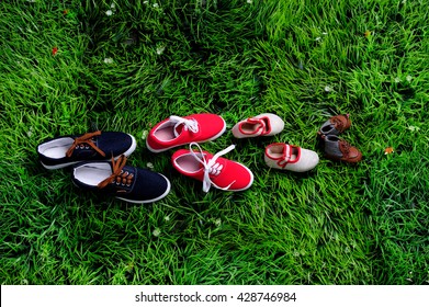four pair of shoes in father big, mother medium and son or daughter small kid size on green grass, representing family, growth, education and togetherness concept 