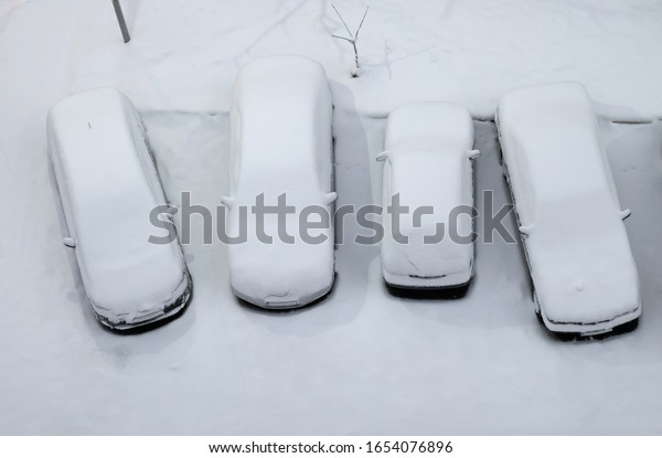 Four parked cars\
covered with snow, top\
view