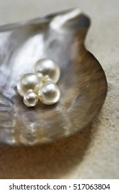 Four Pearls In Open Oyster Shell On Beach Close Up Elevated View