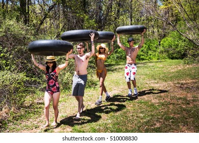 Four People Carrying Inner Tubes Above Heads