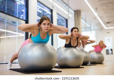 Four People Doing Back Extensions On Swiss Ball During Pilates Training