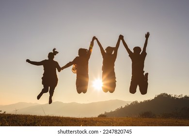 Four people jumping on mountain sunset sky background. 