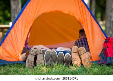 Four people lying in a tent with their legs outside the tent