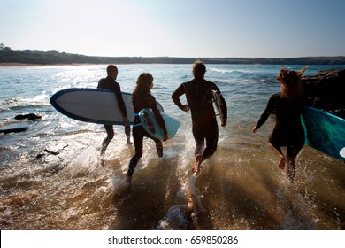 Four People Running Into The Water