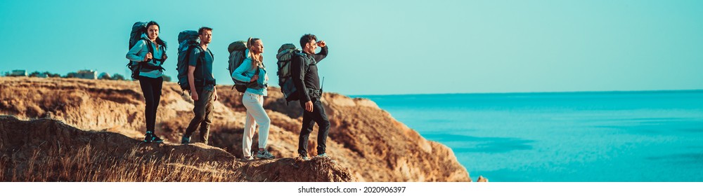 The four people standing on the mountain peak near the sea