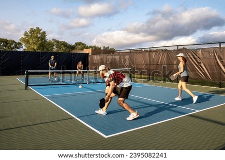 Four pickleball players rally against each other with two at the net ready to return a drive on a dedicated court.