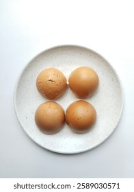 four pieces of broken egg shells on a round white plate. 