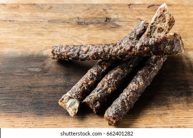 Four pieces of droewors (dried meat) on a wooden board, this is a traditional food snack that can be found in South Africa. 