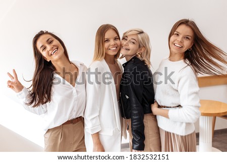 Four positive young women posing with happy faces at the cafe indoors.