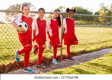 Four pre teen girls in a soccer team looking to camera