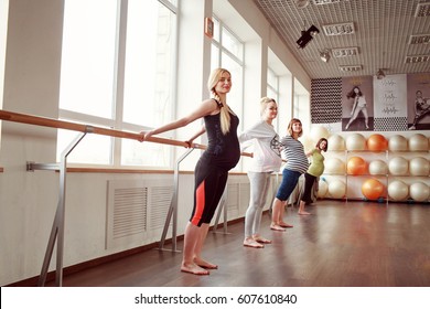 Four pregnant women stretching using barre