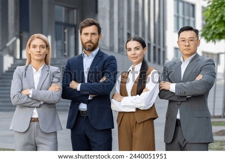 Four professional business individuals posing confidently outdoors, displaying teamwork and corporate success in a modern urban setting.