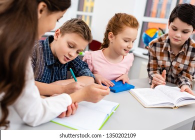 Four pupils with notebook and books at desk in classroom - Powered by Shutterstock