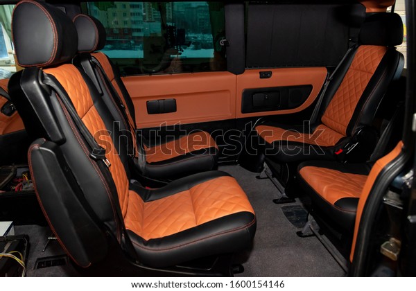Four\
rear seats in a minibus are deployed to each other and tightened in\
black and brown leather with a diamond-shaped stitching thread in a\
workshop for tuning and repairing vehicles. Van\
car.