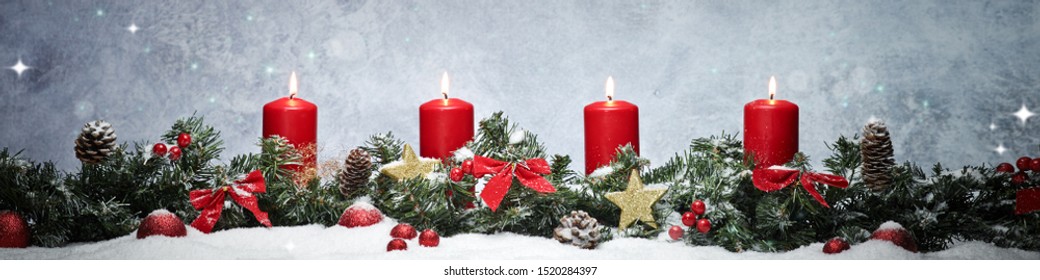 four red burning candles on a pine wreath with christmas decorations ,  show the fourth advent and the holy evening in the snow with a grey sky background with stars in the snow