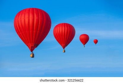 Four Red Hot Air Balloons In Blue Sky With White Clouds