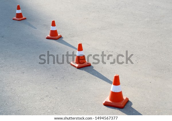 Four road cones on the pavement. Cast a shadow on\
the sun.