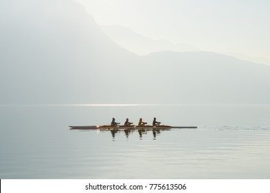 Four rowers on boat floating on sunny morning on background of mountains on lake of Lugano. Concept of healthy lifestyle, water sports. Switzerland. - Shutterstock ID 775613506