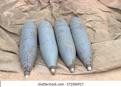 Four Rusty Artillery Shells On The Sand