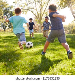 Four schoolboys playing football in the park, square format