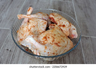 Four Seasoned Raw Whole Chicken Legs In A Glass Heat-resistant Vessel, The Grey Wooden Background