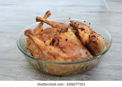 Four Seasoned Roasted Whole Chicken Legs In A Glass Heat-resistant Vessel, The Grey Wooden Background