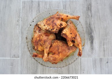 Four Seasoned Roasted Whole Chicken Legs In A Glass Heat-resistant Vessel, The Grey Wooden Background