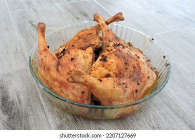 Four Seasoned Roasted Whole Chicken Legs In A Glass Heat-resistant Vessel, The Grey Wooden Background