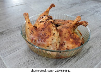 Four Seasoned Roasted Whole Chicken Legs In A Glass Heat-resistant Vessel, The Grey Wooden Background