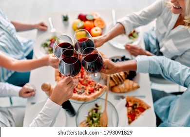 Four Senior Friends Having Dinner At Home. Two Handsome Mature Men And Two Attractive Women Spending Time Together Indoors. Group Of Old Friends Drinking Wine In Modern Apartment.