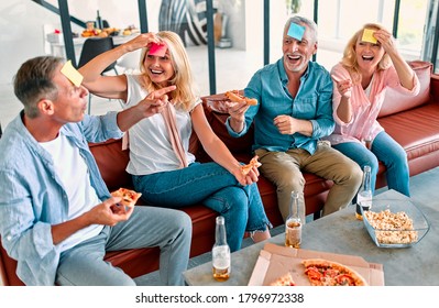 Four senior friends having fun at home.  Group of old friends playing game guess who in modern apartment. Two handsome mature men and two attractive women spending time together indoors. - Powered by Shutterstock