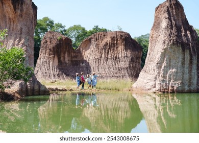 Four senior women friends explore unique rock formations near a calm pond, enjoying a peaceful natural setting. joyful expressions and relaxed postures reflect a deep bond and shared love for nature. - Powered by Shutterstock