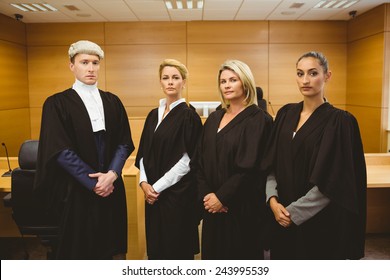 Four serious judges standing while wearing robes in the court room