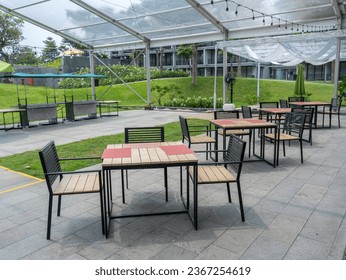 Four sets of empty outdoor dining tables with black metal and wooden materials and red dining mat.