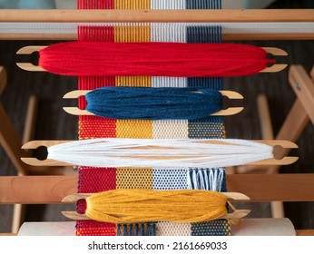 Four shuttles with yarn of different colors on the loom. Weaving shuttles with blue, white, red and yellow threads on the weaving project