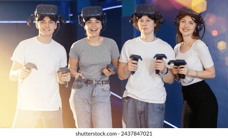 four smiling students with virtual reality devices stand and pose in gaming modern club. future technologies. digital interface - Powered by Shutterstock