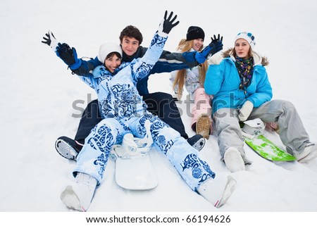 Four snowborders sit on snow and preparing to ride from the hill