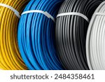 Four Spools of Electrical Wire in Yellow, Blue, Black, and White Colors: A Close-Up Photo of Four Spools of Electrical Wire, Each Wound in a Different Color.