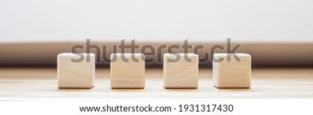 Four square blocks of wood are arranged on the table. A wooden block with copy space for text or symbols is used to make banners. Panorama banner background with copy space.