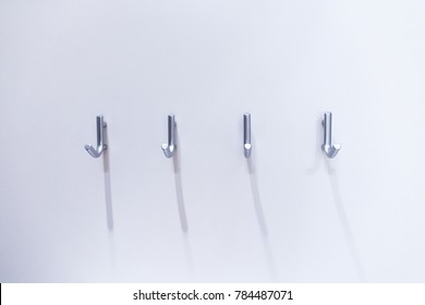 Four steel hangers at white wall