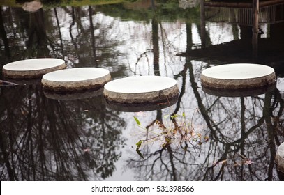 Four Stepping Stones In Japanese Garden Pond With Reflection And Leaves. Horizontal.