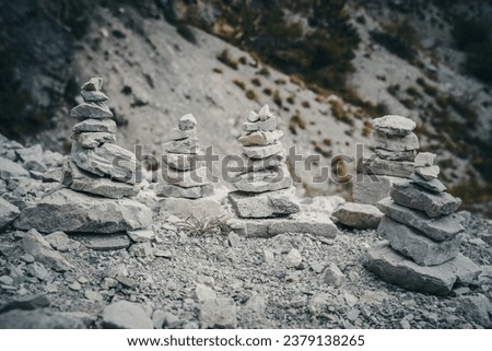 four stone cairns along a hiking path in alpine setting