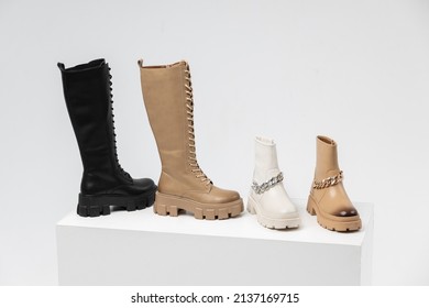 Four Stylish Leather Boots In A Single Copy On The Podium In The Form Of Steps In The Studio On A White Background