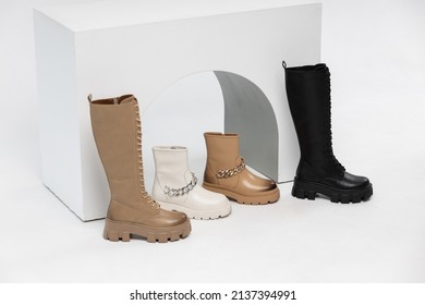 Four Stylish Leather Boots In A Single Copy On The Podium In The Form Of Steps In The Studio On A White Background