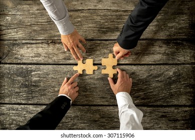 Four successful business men joining two puzzle pieces each being held by two partners, rustic wooden background. Conceptual of merger or creative cooperation of two business companies. - Shutterstock ID 307115906