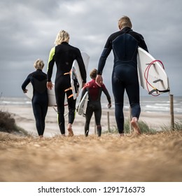 Four Surfers In Wetsuits Walking To Beach With Boards, Denmark, Europe